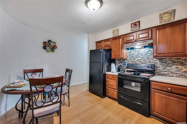 kitchen with black appliances, light wood-type flooring, and backsplash