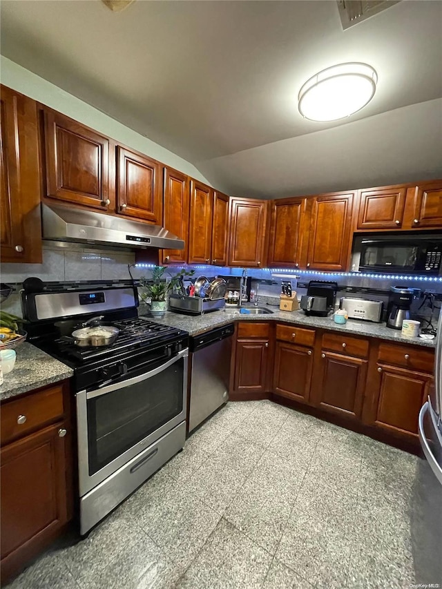 kitchen with tasteful backsplash, stainless steel appliances, vaulted ceiling, sink, and stone countertops