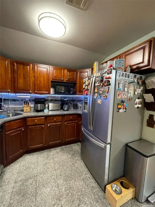 kitchen featuring black appliances, lofted ceiling, and sink