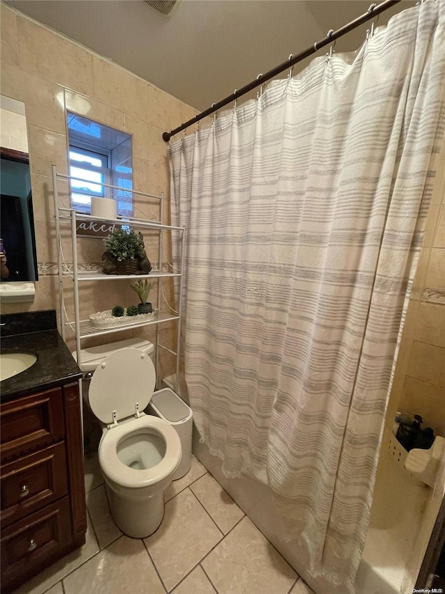 full bathroom with tile patterned floors, vanity, shower / bath combo with shower curtain, tile walls, and toilet