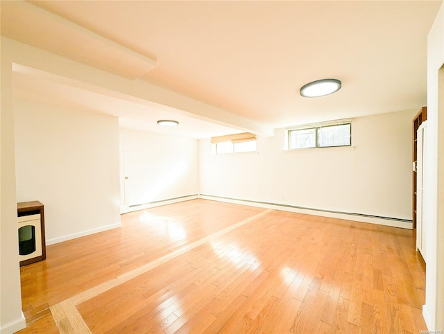 spare room featuring baseboard heating and light wood-type flooring