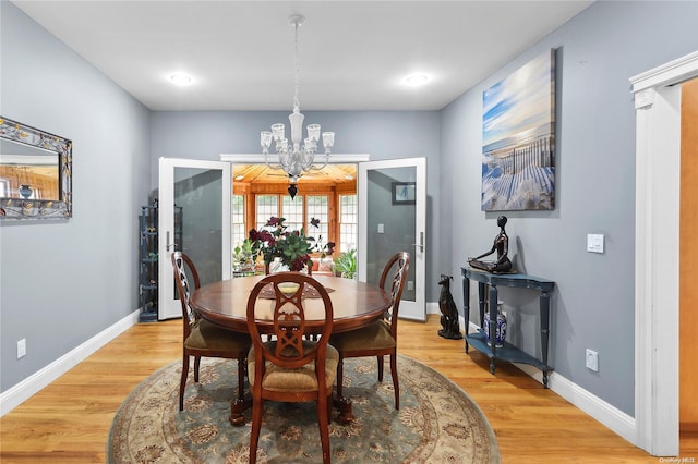 dining space featuring french doors, light hardwood / wood-style floors, and a notable chandelier