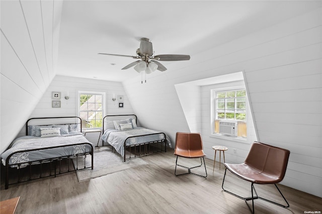 bedroom featuring wood walls, cooling unit, vaulted ceiling, ceiling fan, and light hardwood / wood-style floors