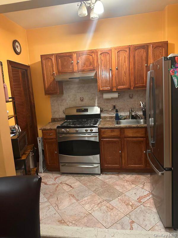 303 Milford St, Brooklyn, NY 11208 - kitchen featuring appliances with stainless steel finishes, a sink, decorative backsplash, and under cabinet range hood