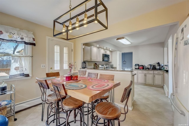 tiled dining room featuring a healthy amount of sunlight, sink, and baseboard heating