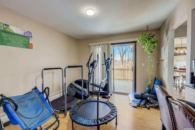 exercise room featuring a notable chandelier and light hardwood / wood-style flooring