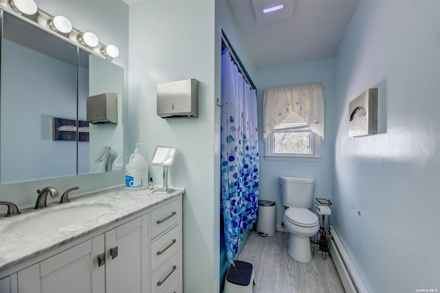 bathroom with hardwood / wood-style flooring, vanity, toilet, and a baseboard radiator