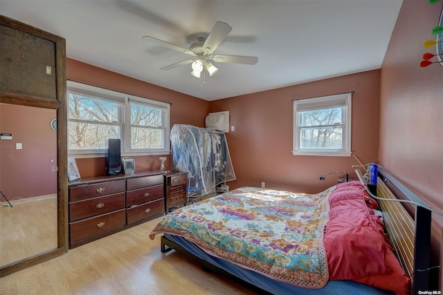 bedroom with ceiling fan, light wood-type flooring, and multiple windows