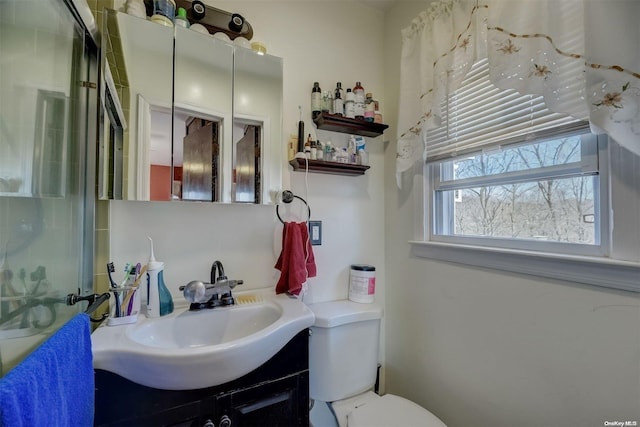 bathroom featuring vanity, toilet, and a shower with door