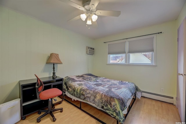 bedroom featuring ceiling fan, light hardwood / wood-style floors, an AC wall unit, and a baseboard heating unit