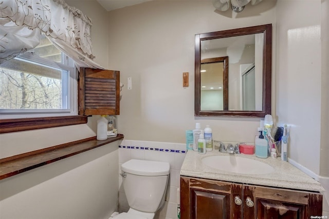 bathroom with vanity, toilet, a shower with door, and tile walls