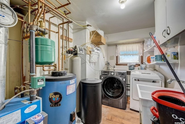 laundry room featuring sink, cabinets, gas water heater, separate washer and dryer, and light wood-type flooring