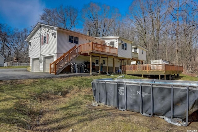 back of property featuring a pool side deck, a garage, and a yard