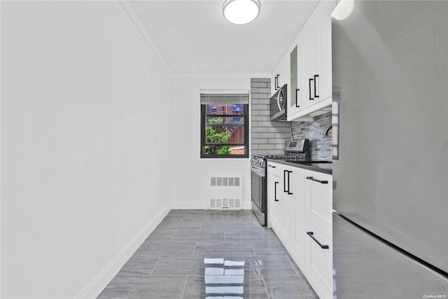 kitchen featuring backsplash, white cabinetry, ornamental molding, and appliances with stainless steel finishes