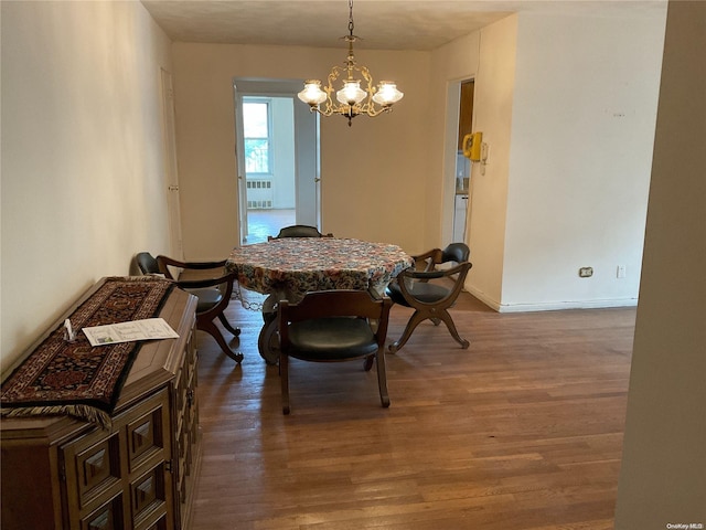 dining room featuring wood-type flooring, radiator heating unit, and a chandelier