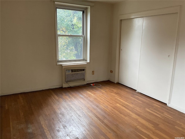 unfurnished bedroom with light wood-type flooring and a wall unit AC