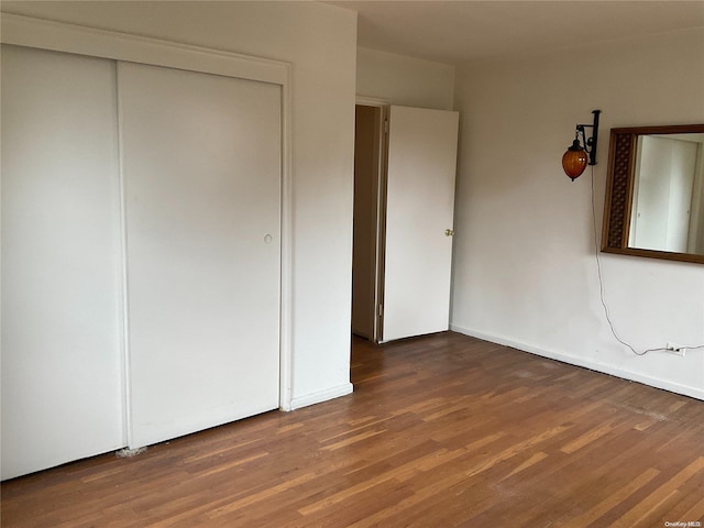 unfurnished bedroom featuring a closet and dark wood-type flooring