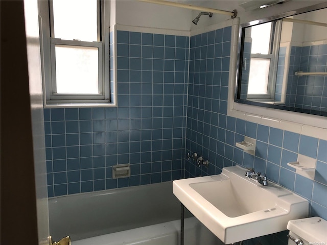 full bathroom featuring toilet, tiled shower / bath, sink, and tile walls