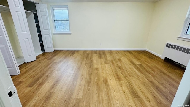 unfurnished bedroom with radiator heating unit and light hardwood / wood-style flooring