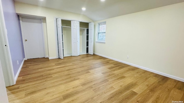 unfurnished bedroom with light hardwood / wood-style floors and lofted ceiling