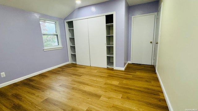 unfurnished bedroom featuring hardwood / wood-style floors and lofted ceiling