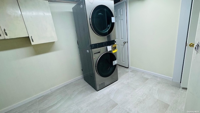 laundry room featuring cabinets and stacked washer and clothes dryer