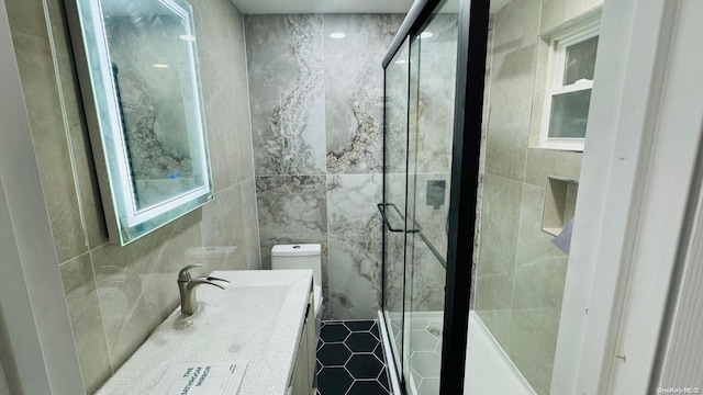 bathroom featuring vanity, toilet, a shower with shower door, and tile walls