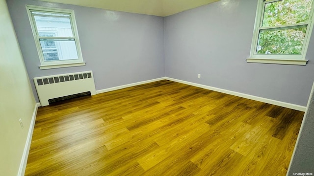 empty room with hardwood / wood-style flooring and radiator heating unit