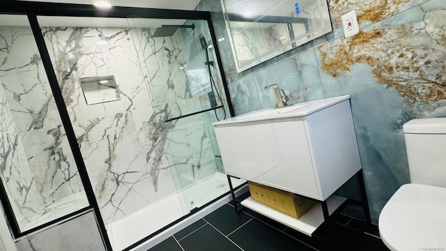 bathroom with a shower with door, vanity, tile walls, and toilet