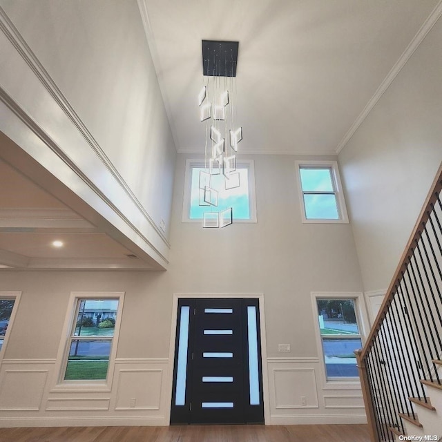 foyer featuring a towering ceiling, ornamental molding, and hardwood / wood-style flooring