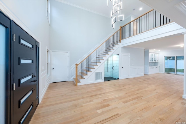 foyer entrance featuring a high ceiling, light hardwood / wood-style floors, and crown molding