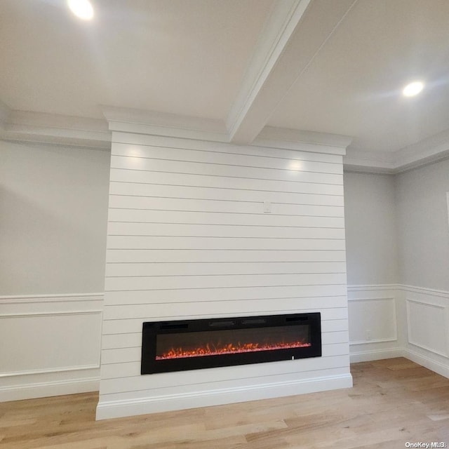 interior details with hardwood / wood-style floors, a large fireplace, ornamental molding, and beam ceiling