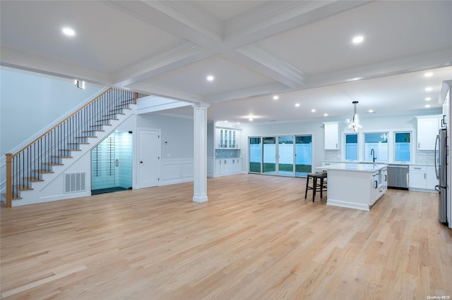 unfurnished living room featuring crown molding, sink, light hardwood / wood-style floors, a notable chandelier, and beam ceiling