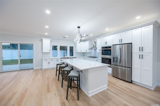 kitchen with appliances with stainless steel finishes, light wood-type flooring, white cabinetry, and hanging light fixtures