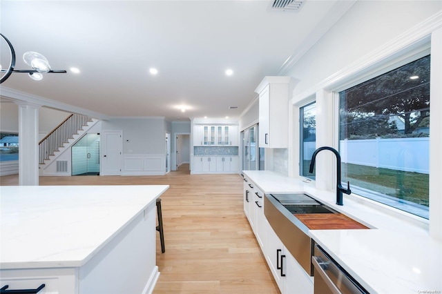 kitchen featuring light wood-type flooring, light stone counters, crown molding, sink, and white cabinetry