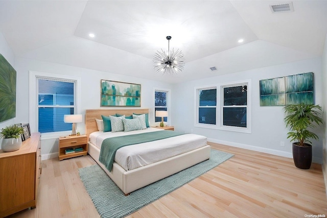 bedroom featuring light hardwood / wood-style floors, lofted ceiling, and a chandelier