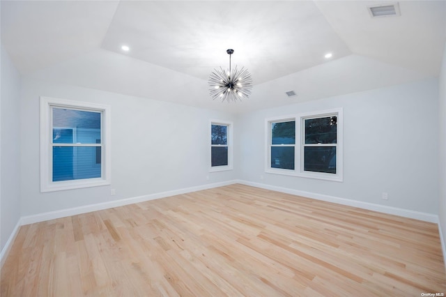 empty room featuring a chandelier, light hardwood / wood-style floors, and lofted ceiling