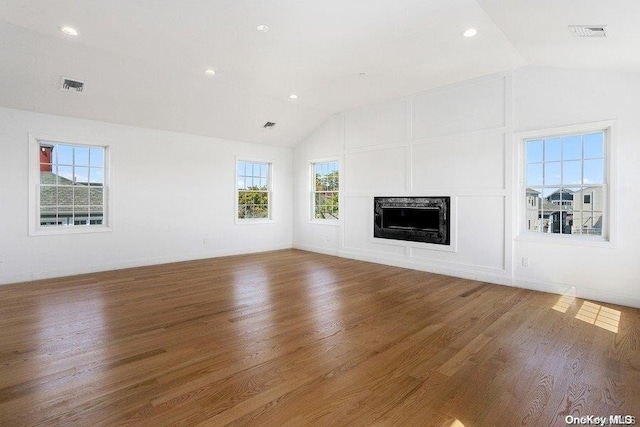 unfurnished living room featuring hardwood / wood-style floors, vaulted ceiling, and plenty of natural light