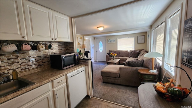 kitchen featuring dark carpet, white dishwasher, sink, decorative backsplash, and white cabinetry