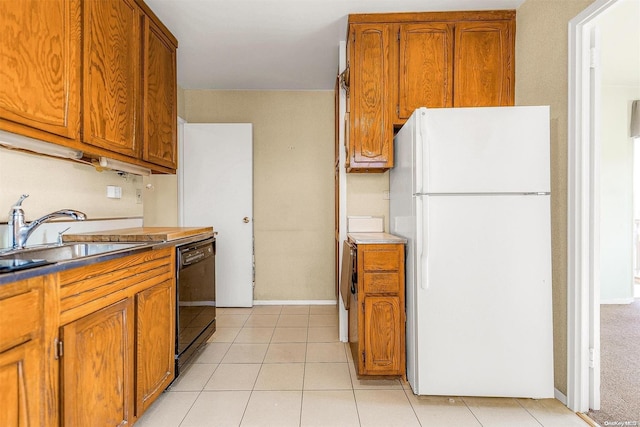 kitchen with light tile patterned flooring, dishwasher, sink, and white fridge