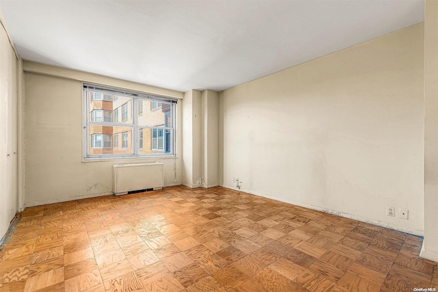 spare room featuring light parquet floors and radiator