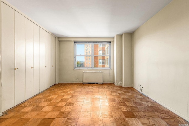 unfurnished bedroom featuring radiator heating unit and a closet