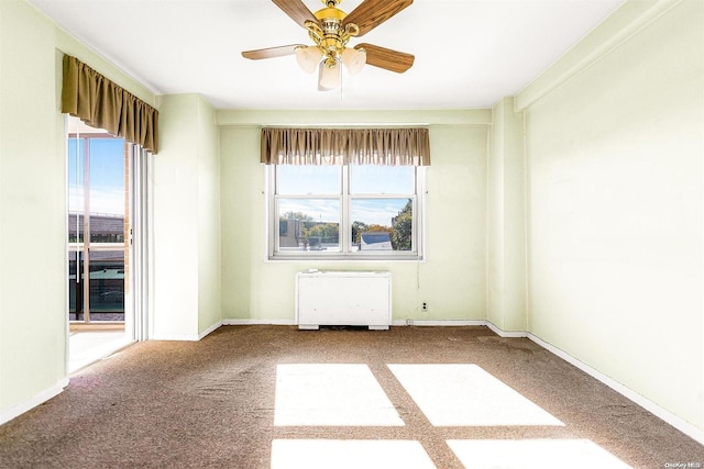 empty room featuring ceiling fan, radiator heating unit, and carpet floors