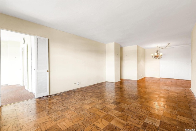 empty room with parquet floors and a notable chandelier