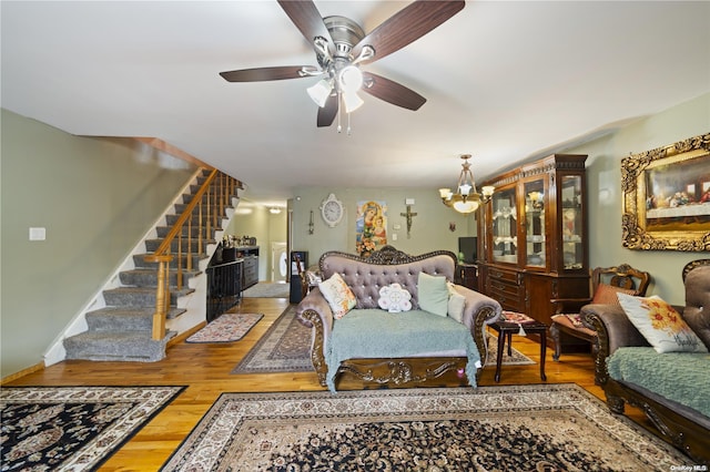 living room with ceiling fan with notable chandelier and hardwood / wood-style flooring