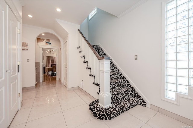 corridor featuring light tile patterned floors, plenty of natural light, and ornamental molding