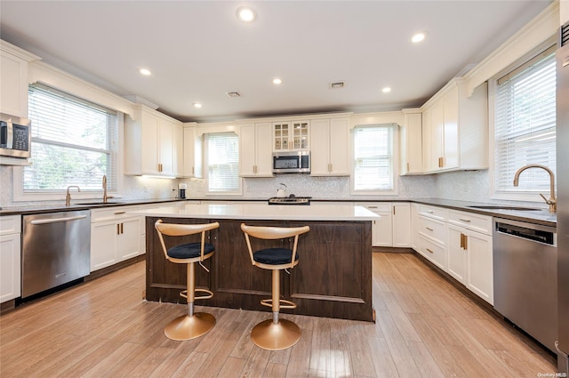 kitchen with a healthy amount of sunlight, a kitchen island, light hardwood / wood-style floors, and stainless steel appliances