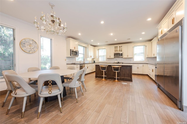 dining area with crown molding, sink, a chandelier, and light wood-type flooring