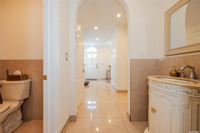 bathroom featuring tile patterned flooring, crown molding, toilet, vanity, and tile walls