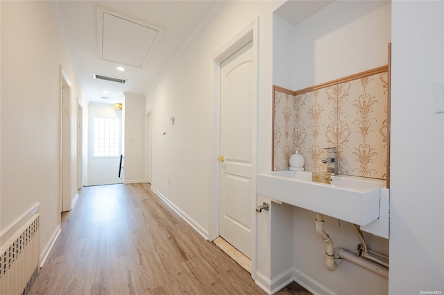 hallway featuring crown molding, sink, radiator, and light hardwood / wood-style flooring